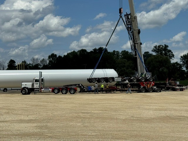 Crane lifting a propane bullet tank off its transport trailer
